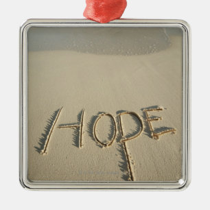 The word 'Hope' sand written on the beach with Metal Tree Decoration
