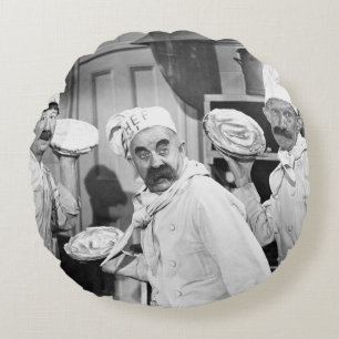 Three chefs holding pies for a fight in the kitche round cushion