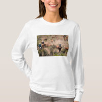 Three cowboys and cowgirls driving cattle
