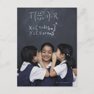Three girls in classroom whispering postcard