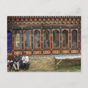 Three men sit on a bench at the Memorial Chorten Postcard