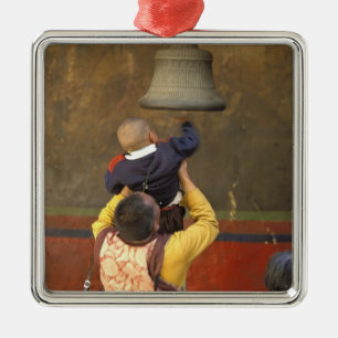 Tibetan Buddhist monk lifting a boy to ring a Metal Tree Decoration