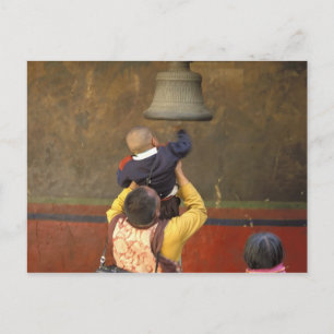 Tibetan Buddhist monk lifting a boy to ring a Postcard