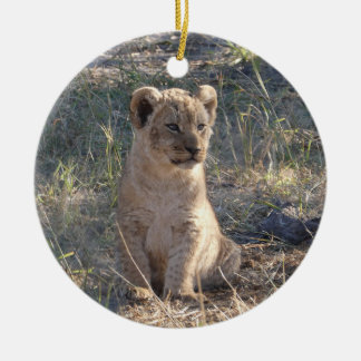 Tiny African lion cub sitting in the grass Ceramic Tree Decoration