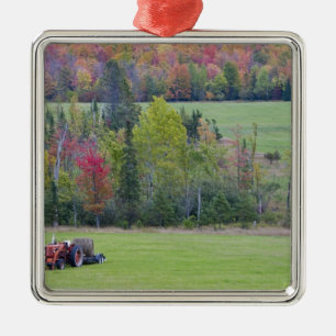 Tractor with hay bale in green field with metal tree decoration