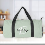 Trendy Sage Green Black White Script Monogram  Duffle Bag<br><div class="desc">This personalised duffel bag features a monogram and first name in modern black and white script on a stylish sage green background.</div>