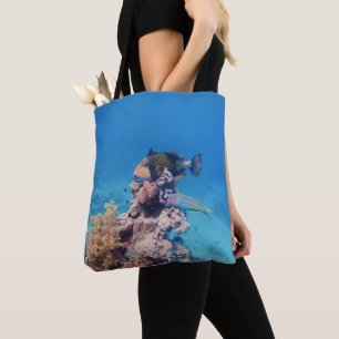 Triggerfish rests on a coral block at coral reef   tote bag