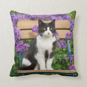 Tuxedo cat sitting on a garden chair with flowers cushion