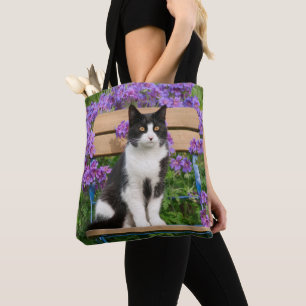 Tuxedo cat sitting on a garden chair with flowers tote bag