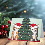 Two Corgi Christmas Tree Dog Santa Hat Cute Holiday Card<br><div class="desc">These beautiful Pembroke Welsh Corgi dogs have their heads tilted inside of a cute Santa Claus hat. The two pups are sitting in front of a pretty Christmas tree decorated with colourful ornaments. A lovely corgis holiday card with a wonderful drawing of a tricolor and a red and white corgi...</div>