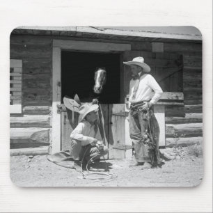 Two cowboys standing next to a barn with a horse mouse mat