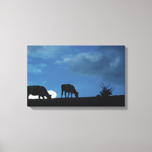 Two cows in silhouette grazing on hillside canvas print (Front)