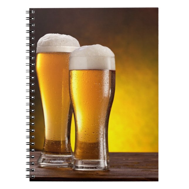 Two glasses of beers on a wooden table notebook (Front)