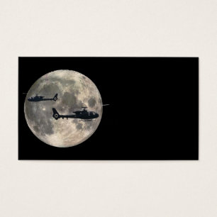 two helicopters silhouetted by a full moon