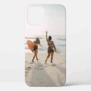 Two women walking towards the ocean carrying surfb iPhone 12 case