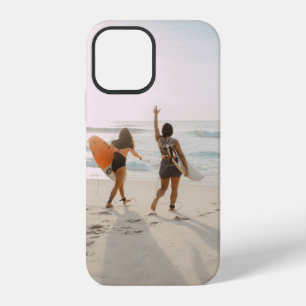Two women walking towards the ocean carrying surfb iPhone 12 case