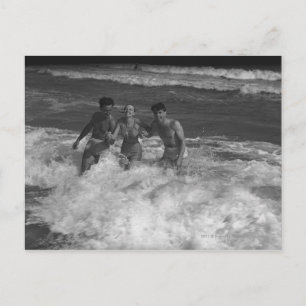 Two young men and woman playing in wave B&W Postcard