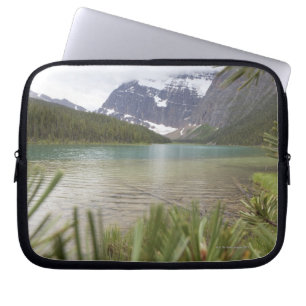 View past pine branches to mountain lake laptop sleeve