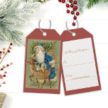 Vintage Santa Claus Merry Christmas Gift Tags<br><div class="desc">Wonderful vintage Santa Claus wearing a blue coat and hat with reindeer and tree. The reindeer is carrying santa's sack with toys in it. The design is from the early 1900s. See coordinating items in our shop,  Enchanted Finch.</div>