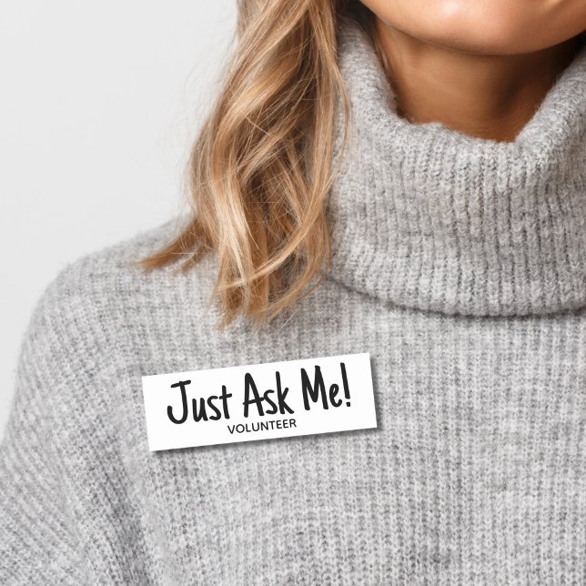 Volunteeer Ask Me Simple Name Tag (Woman wearing gray sweater with black and white "just ask me" volunteer name tag badge.)