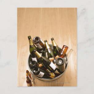 Waste bin full of empty champagne bottles on postcard