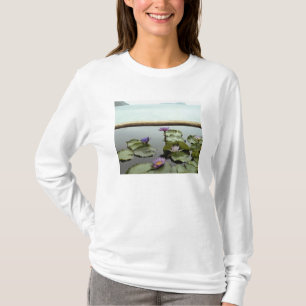Water lilies in pond by ocean T-Shirt