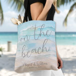 Watercolor On The Beach Wedding Tote Bag<br><div class="desc">Simple Seaside Watercolor Tote Bag. Celebrate your seaside wedding with this double-sided tote bag featuring a calming watercolor design in soft shades of blue and tan. The slightly abstract coastal artwork captures the relaxed, natural feel of the ocean meeting the shore, creating a serene, beach-inspired look. On the bag, “On...</div>
