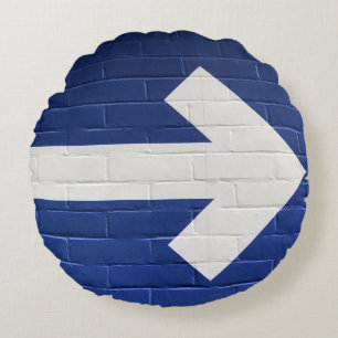 White arrow painted on brick wall round cushion