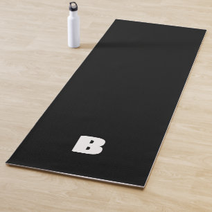 White bold initial on black yoga mat