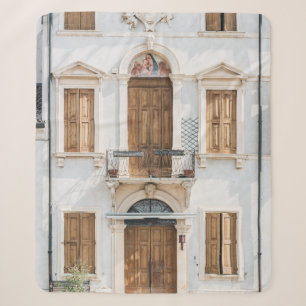 WHITE CONCRETE BUILDING WITH WOODEN DOORS AND WIND SHERPA BLANKET