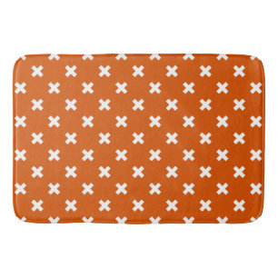 White cross stitches on burnt orange bath mat