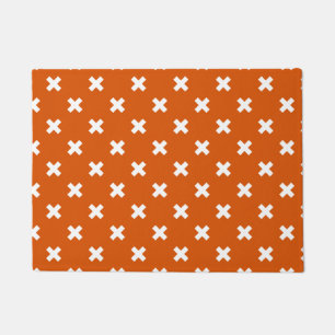 White cross stitches on burnt orange doormat