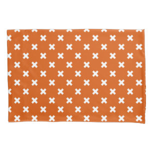 White cross stitches on burnt orange pillowcase