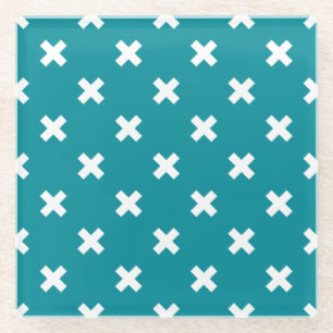 White cross stitches on teal glass coaster