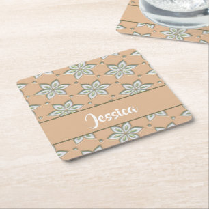 White engraved flowers on tan square paper coaster