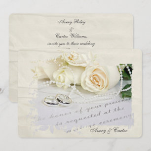 white roses and rings on wedding invite