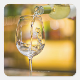 White wine is poured from bottle in restaurant. square sticker