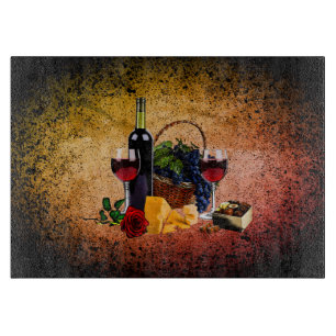 Wine glasses, bottle, grapes, cheese, chocolates cutting board