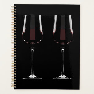 Wine glasses with red wine on black planner