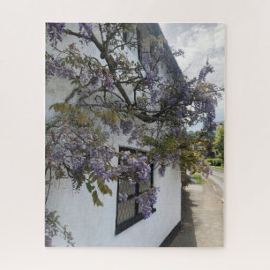Wisteria growing against a white-walled cottage jigsaw puzzle