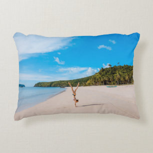 Woman doing acrobatic on seashore near mountain ra decorative cushion