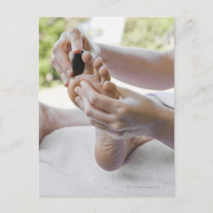 Woman getting foot massage with hot stone postcard