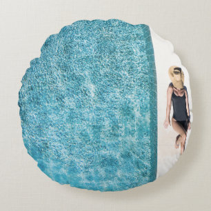 Woman in black bikini bottom and white sun hat sta round cushion