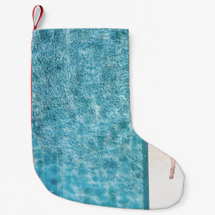 Woman in black bikini bottom and white sun hat sta small christmas stocking