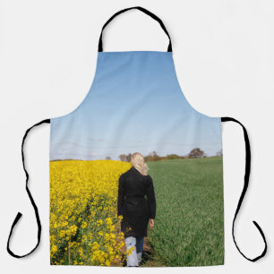 Woman in black coat standing on green grass field  apron