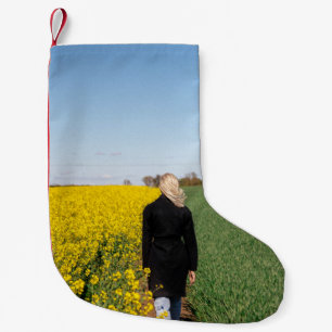 Woman in black coat standing on green grass field  small christmas stocking