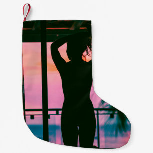 Woman in black tank top and pants standing on blac small christmas stocking