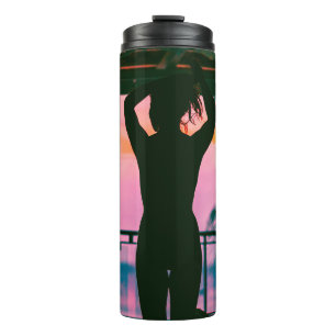 Woman in black tank top and pants standing on blac thermal tumbler