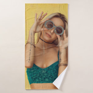 Woman in blue bralette holding sunglasses putting bath towel