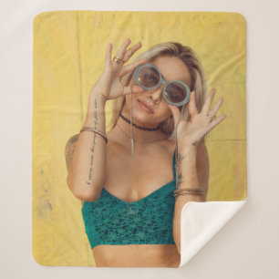 Woman in blue bralette holding sunglasses putting  sherpa blanket